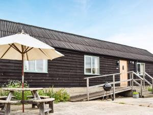 a house with a table and an umbrella and a bench at The Long Barn in Little Baddow