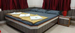 Una cama con toallas blancas encima. en Sai Raghunandan Guest House, en Shirdi