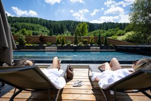 two people laying in chairs next to a swimming pool at Tevini Dolomites Charming Hotel in Commezzadura +99 photos