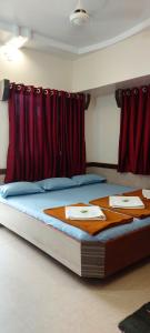 a bedroom with a bed with red curtains at Sai Raghunandan Guest House in Shirdi