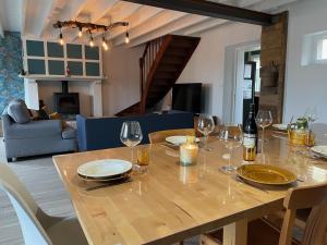 uma mesa de madeira com copos de vinho e uma sala de estar em Les Limicoles maison proche mer em Gouville-sur-Mer