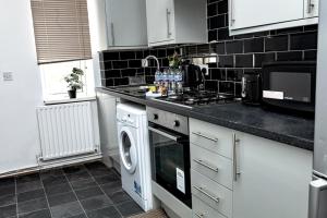 a kitchen with a stove top oven next to a dishwasher at Silver Apartment 2 Bed Flat Leicester City Centre in Leicester
