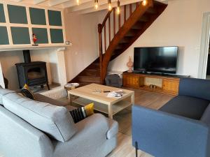 ein Wohnzimmer mit Sofa und Fernseher in der Unterkunft Les Limicoles maison proche mer in Gouville-sur-Mer