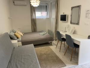 een kleine kamer met een bed en een bureau met stoelen bij Sunrise Apartment in Hajdúszoboszló