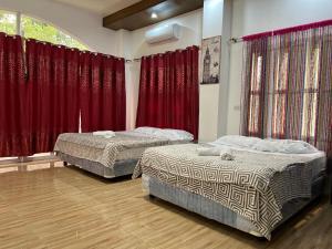 2 camas en una habitación con cortinas rojas en kiliog Valley Inn, 