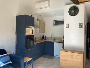 a kitchen with blue cabinets and a microwave at Maisonnette avec jardinet et parking - Velleron in Velleron