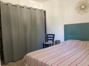 a bedroom with a bed and a gray curtain at Maisonnette avec jardinet et parking - Velleron in Velleron