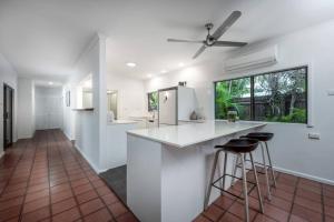 a white kitchen with a counter and stools at Talpa Tropix- 5 min stroll to beach in Palm Cove