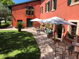 eine Terrasse mit Tischen, Stühlen und einem Sonnenschirm in der Unterkunft Relais Corte Bercelli in Valeggio sul Mincio