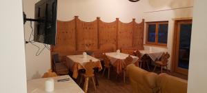 una sala da pranzo con tavoli, sedie e TV di Fattoria Meneguto Agriturismo Degasper Giorgio a Cortina dʼAmpezzo