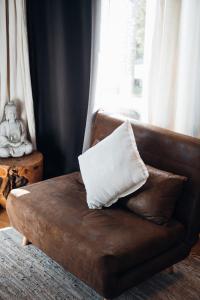 a pillow sitting on a brown leather couch with a window at Mas des Cigales in Orgon