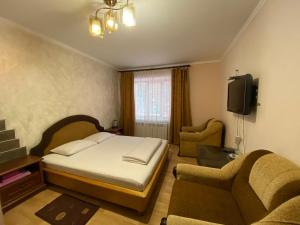 een slaapkamer met een bed, een bank en een tv bij Boguslavl' in Bohuslav