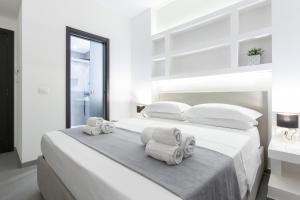 a white bedroom with a bed with towels on it at Suite Palermo Apartment in Palermo