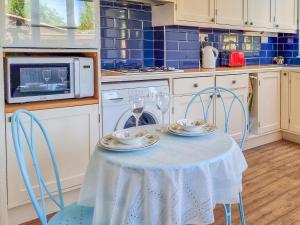 a kitchen with a table with two chairs and a microwave at Pear Tree Cottage in Bath