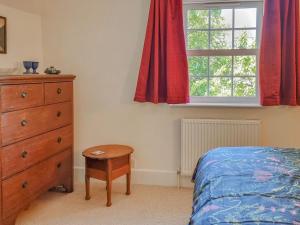 a bedroom with a bed and a dresser and a window at Pear Tree Cottage in Bath