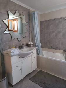 uma casa de banho com um lavatório, uma banheira e um espelho. em Anna's Home em Hermópolis
