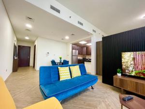 uma sala de estar com um sofá azul e uma televisão em Elite Private Residential Apartment in a Prime Location Al Reem Island - 1301 em Abu Dhabi