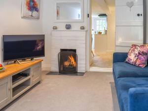 a living room with a fireplace and a tv at Lilliput Cottage in Wangford