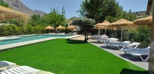 a lawn with chairs and a swimming pool with a resort at Cortijo el Cercadillo in Bedmar