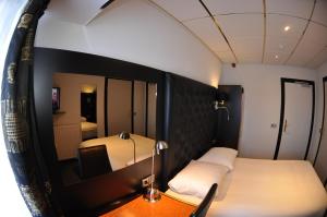 een kleine kamer met een bed en een spiegel bij Hotel Le Beau Rivage in Middelburg