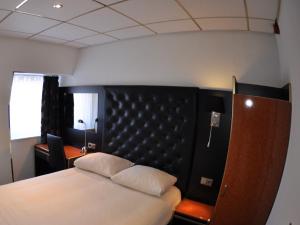 een slaapkamer met een bed met een zwart hoofdeinde bij Hotel Le Beau Rivage in Middelburg