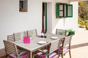 a wooden table with chairs and wine bottles on it at The Captain's Nook Spiliska in Blato