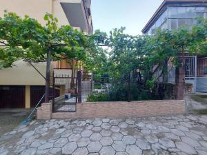 uma cerca com árvores em frente a um edifício em White grapes apartment em Petrich