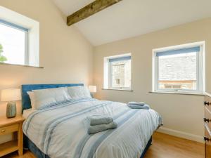 a bedroom with a large bed with two windows at Courtyard Cottage - Uk39179 in Rossendale
