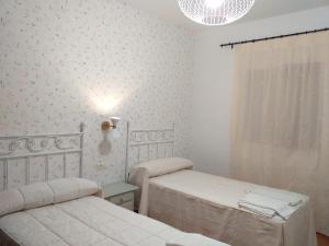 a white room with two beds and a window at Cortijo el Cercadillo in Bedmar