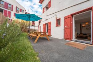 a picnic table with an umbrella next to a building at GARDEN - Utopy Hostel in Biarritz