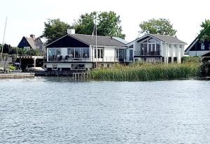 a house on the shore of a body of water at Plassenzicht Logies & Sloepverhuur in Loosdrecht