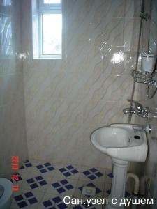 baño con lavabo blanco y ventana en Asfandiar Hotel, en Karakol