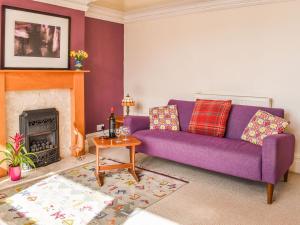 a purple couch in a living room with a fireplace at Fell Mount in Grange Over Sands