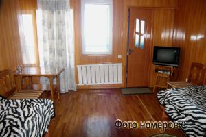 a room with two beds and a table and a television at Asfandiar Hotel in Karakol