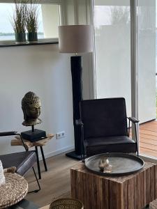a living room with a black chair and a table at Plassenzicht Logies & Sloepverhuur in Loosdrecht