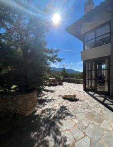 a stone patio with the sun shining on a building at Plethora Arachova Luxury Chalet in Arachova