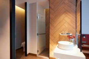 a bathroom with a white sink and a shower at Centara Life Hotel Bangkok Phra Nakhon in Bangkok