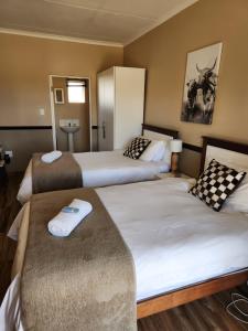 Weaver's Nest Country Inn في Wakkerstroom: غرفة فندقية تحتوي على سريرين في الغرفة