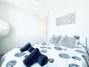 een bed met zwarte en witte lakens en kussens bij Le White Cosy à 5 minutes du Lac avec parking privatif gratuit in Annecy
