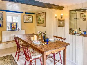 a dining room with a wooden table and chairs at Plum Tree Cottage in Fontmell Magna