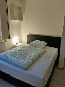 a bed with a blue comforter and a pillow at Renovierte Ferienwohnung in Nienburg Erichshagen in Erichshagen