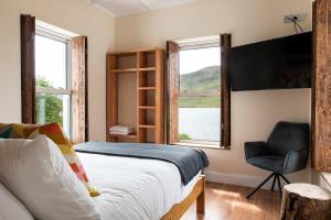 a bedroom with a bed and a chair and a window at Kylemore House boutique apartments - Fishermans Perch in Kylemore