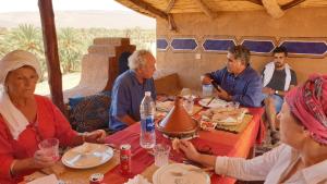 a group of people sitting around a table eating at Maggaman Guest House in Tafraoute Sidi Ali