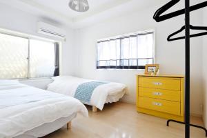 1 dormitorio con 2 camas y vestidor amarillo en Third&Place Namba_Ashiharabashi/芦原橋, en Osaka