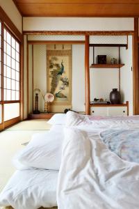 a bedroom with white sheets on a bed at Third&Place Namba_Ashiharabashi/芦原橋 in Osaka