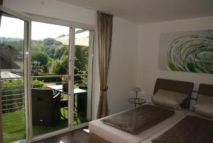 a bedroom with a bed and a balcony with a view at Ferienwohnung Sternenwald in Alf