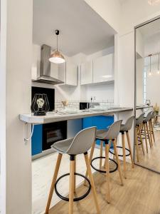a kitchen with white and blue cabinets and bar stools at Appartement de charme: La rochelle/vieux port in La Rochelle