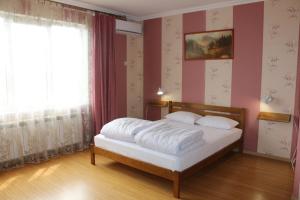 a bedroom with a white bed with pink walls and a window at Sweet Home Hostel in Chernivtsi