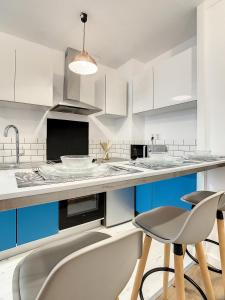 a kitchen with white cabinets and blue chairs at Appartement de charme: La rochelle/vieux port in La Rochelle