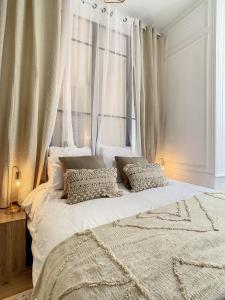 a large white bed with two pillows in front of a window at Appartement de charme: La rochelle/vieux port in La Rochelle